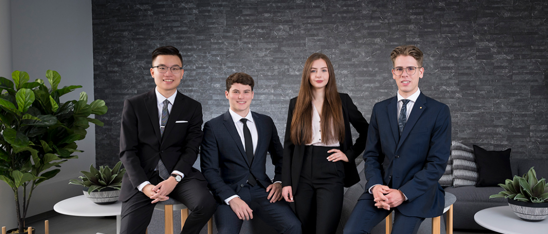 Five Asper students dressed in suits looking at the camera.