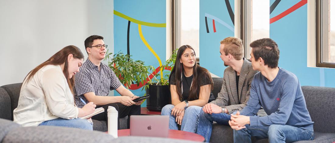 A group of five students sitting on couches in a study lounge at the Asper School of Business.