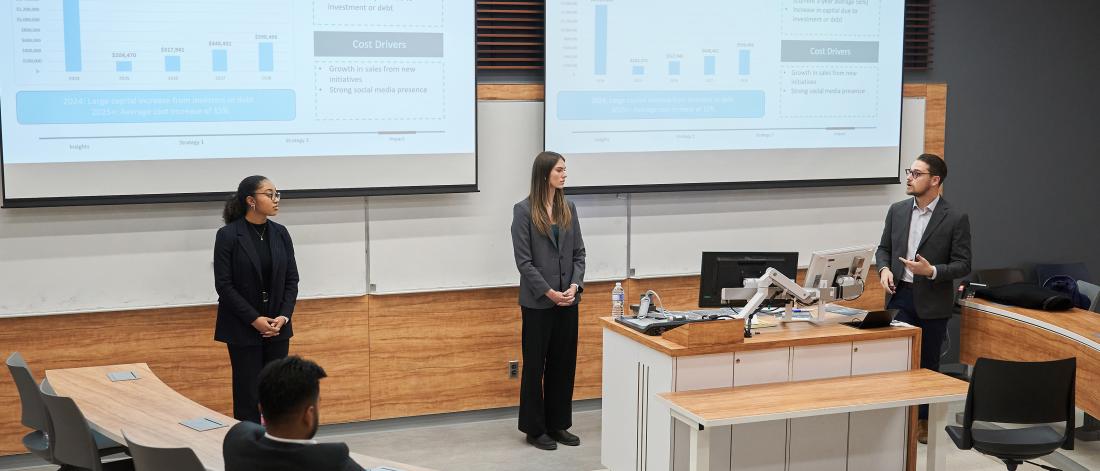 three people standing presenting in front of screen