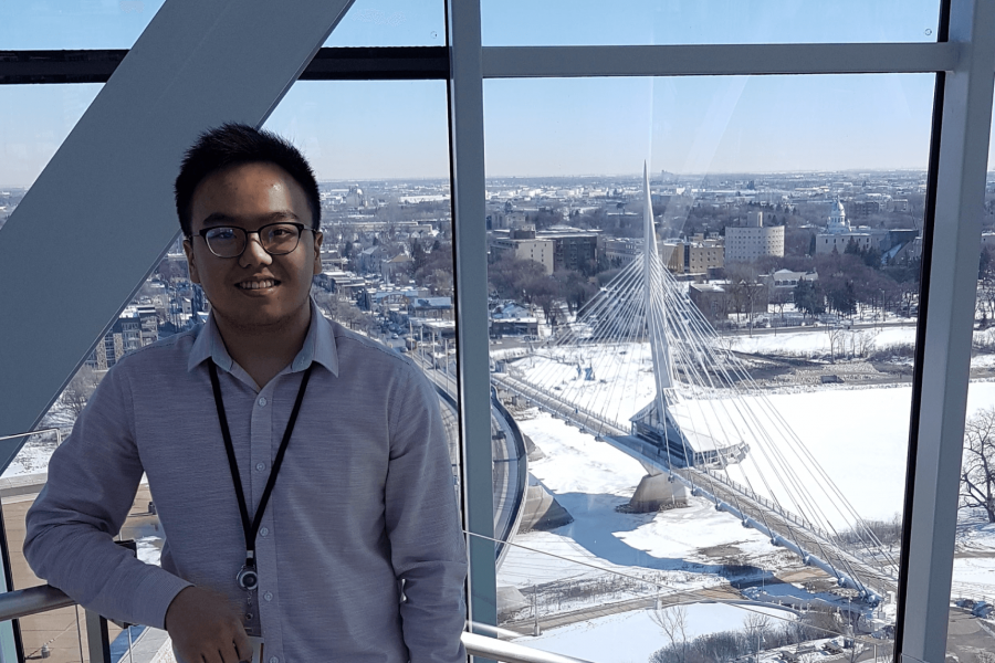 An Asper student stands in front of a window with a scenic winter view of Winnipeg Manitoba.