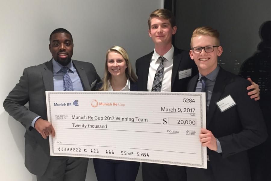Four actuarial students hold up a giant cheque they were awarded.