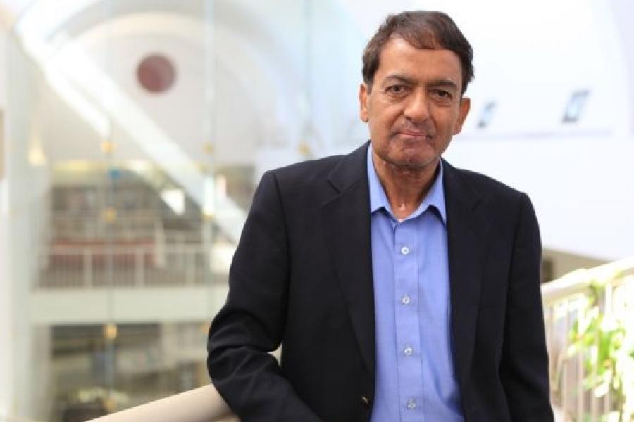Professional shot of Professor Emeritus Suresh Bhatt standing on Asper's third floor