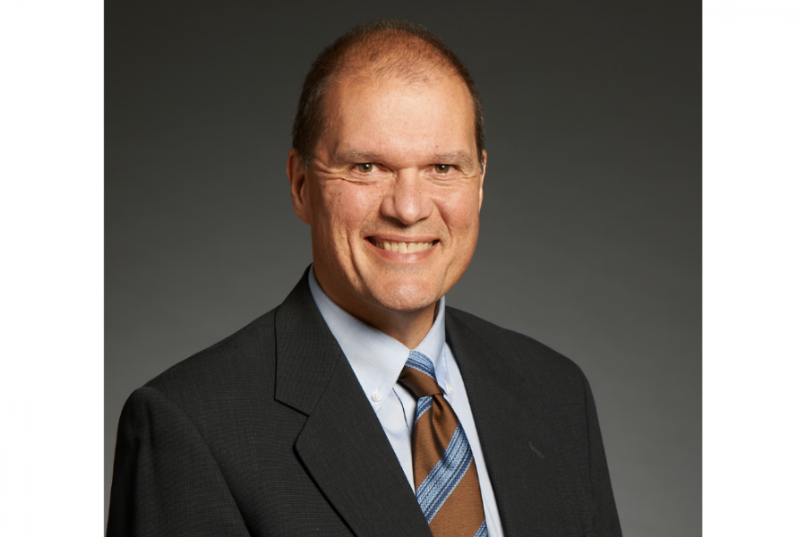 Professional headshot of Executive in Residence Dan Torbiak wearing a black suit and brown, blue striped tie