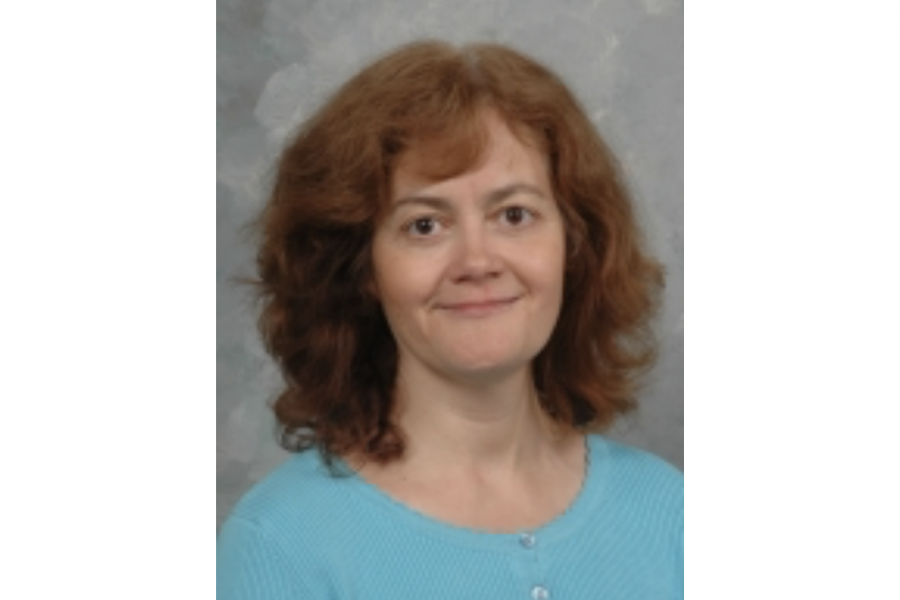 Associate Professor Janet's professional portrait. She wears a coral blue sweater.