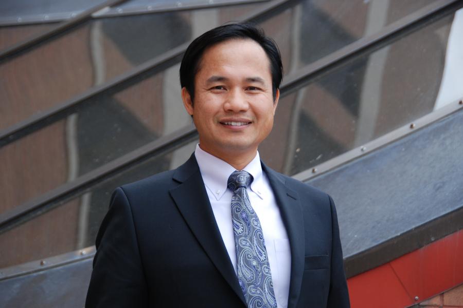 Professor Jeffrey Pai's photo in front of Asper building. He wears a professional suit