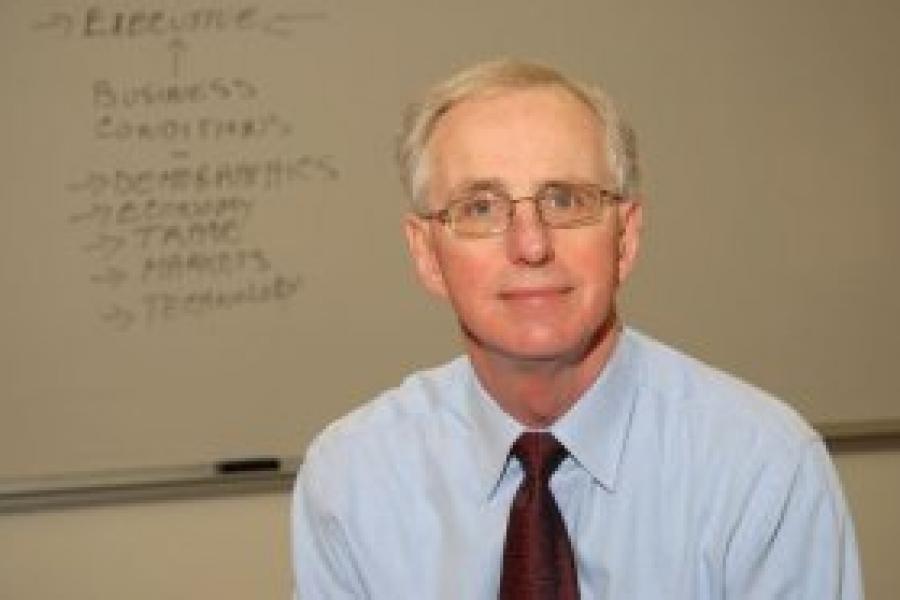 Professor John McCallum's shoot at a lecture hall. He wears a blue shirt and red tie