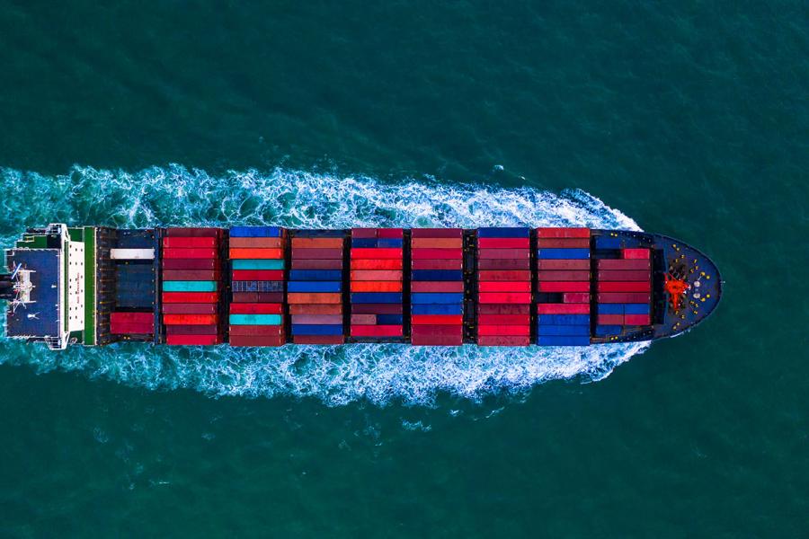 Birds eye view of a ship carrying colourful red, blue, and teal shipping containers.