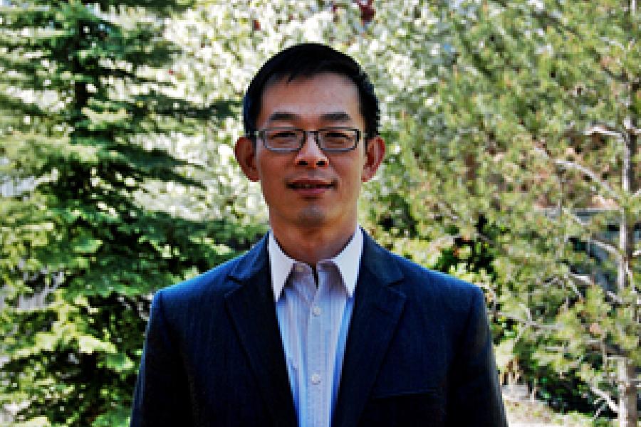 photo of associate professor Wenlong Yuan taken in park. He wears glasses and a blue blazer.