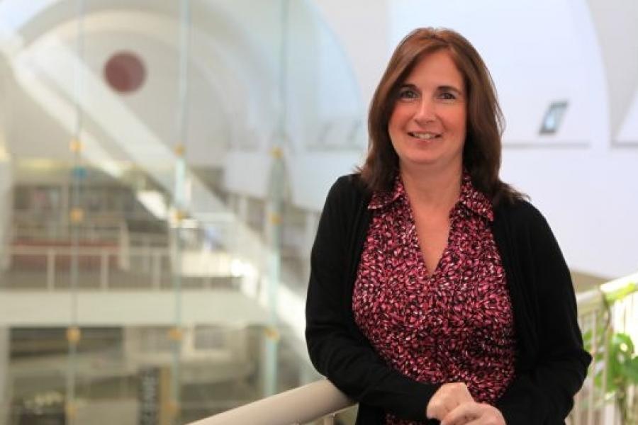 Siobhan leaning on the handrail. She wears a black blazer & a red shirt with white dots pattern