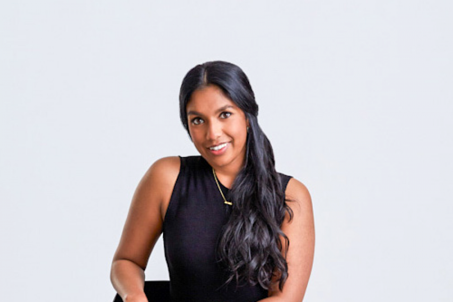 Woman with dark long hair and black sleeveless shirt smiling.