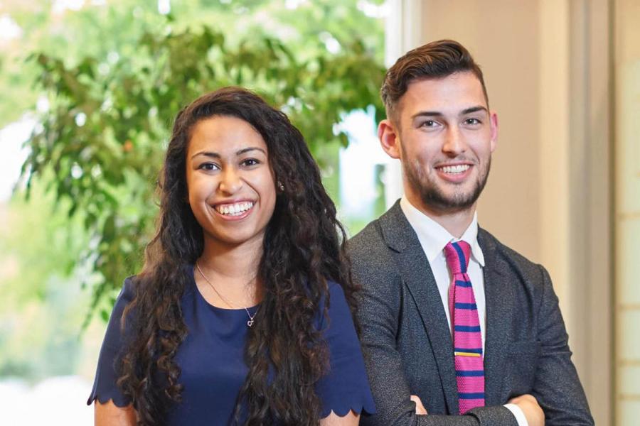 Two students dress in business attire smiling at camera. 