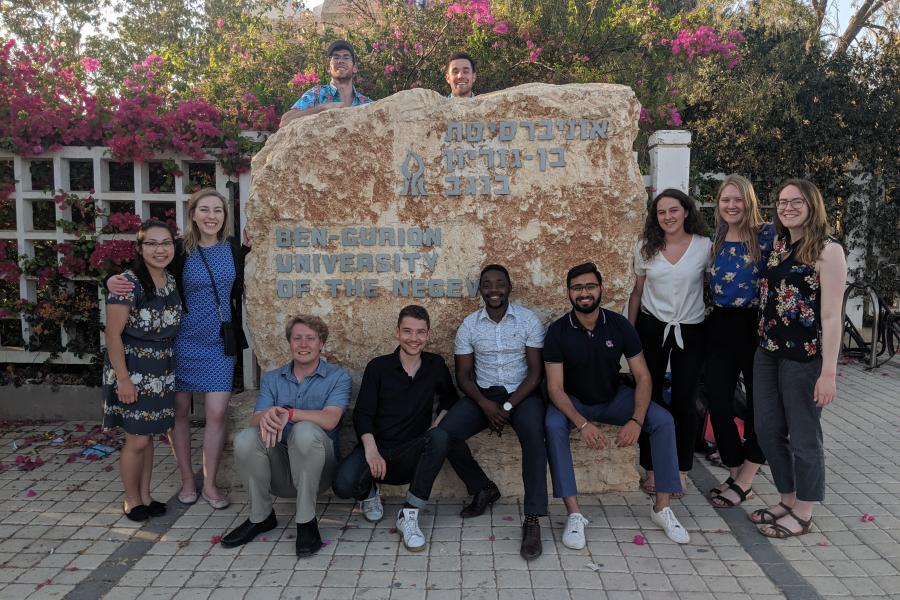 A group of young people in front of the Ben Gurion University campus sign.
