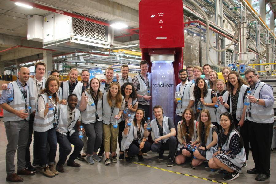 Group of people in blue vests at a Soda Stream factory.