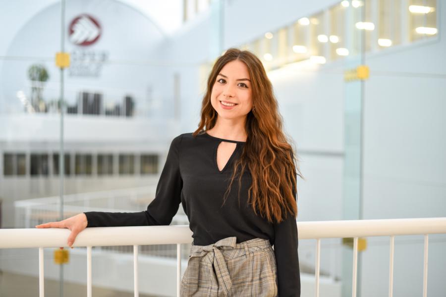 Kiara Goring, Asper staff, wearing a black shirt, grey pants, smiling.