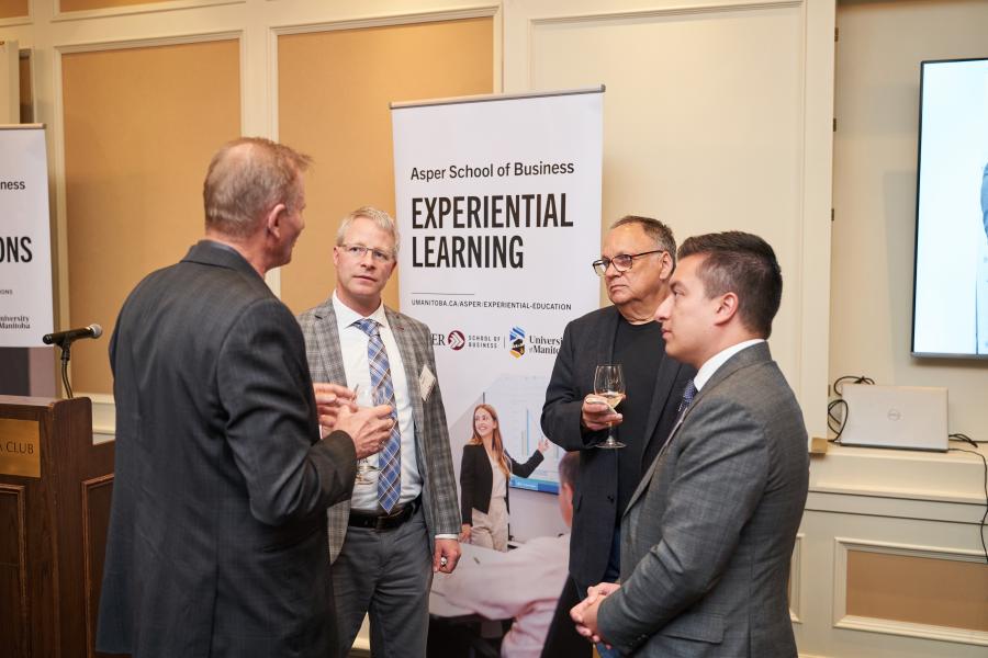 Business professionals having a conversation in front of an Experiential Learning banner