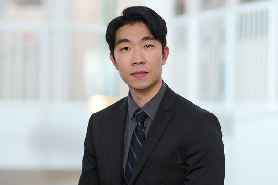 Man wearing black suit and grey shirt with tie. Looking at camera.