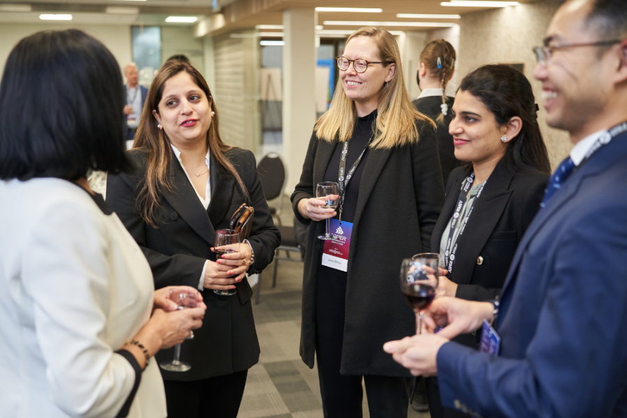 Image of women standing around networking and drinking wine. 