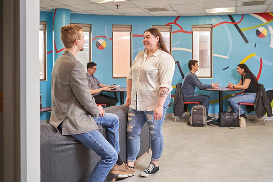 Several students talking in a student study lounge at the Asper School of Business.