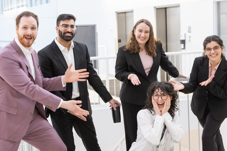 A group of students jokingly pose with their teammate in the middle.
