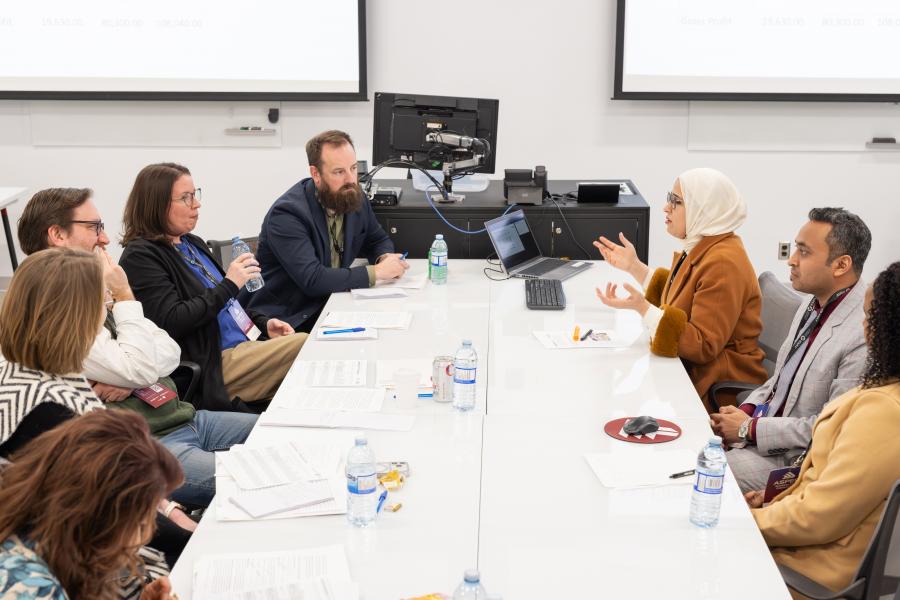 A group of people sit at a boardroom table presenting an idea.