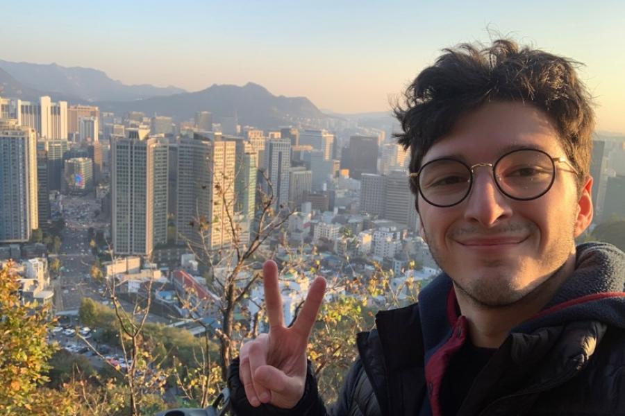 Young man making a peace sign with Asian city in background