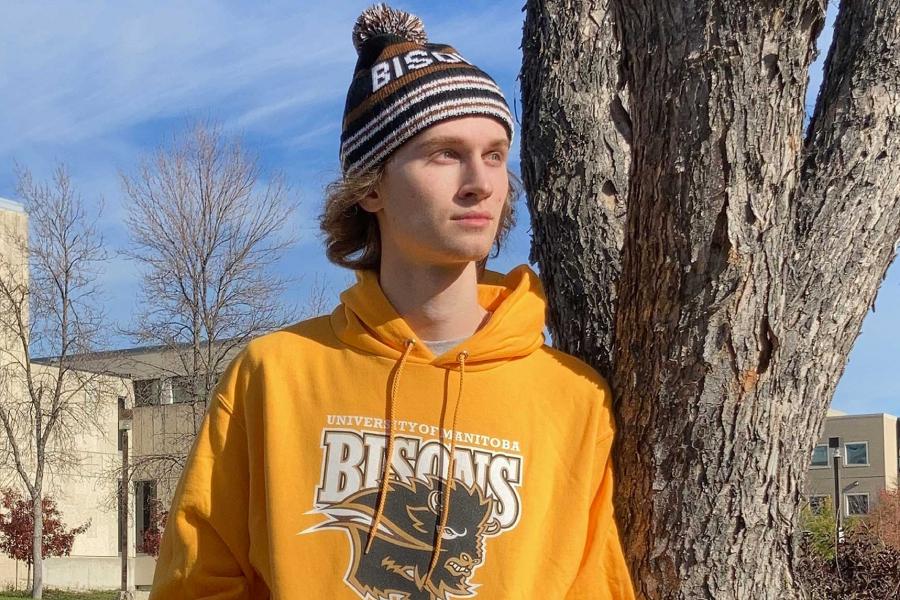 A student wearing a yellow University of Manitoba Bisons hoodie and a brown Bisons hat.