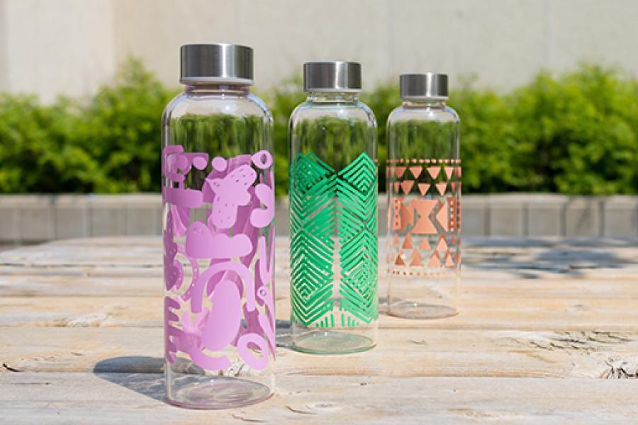 Three colourful water bottles displayed outdoors in the sunshine.