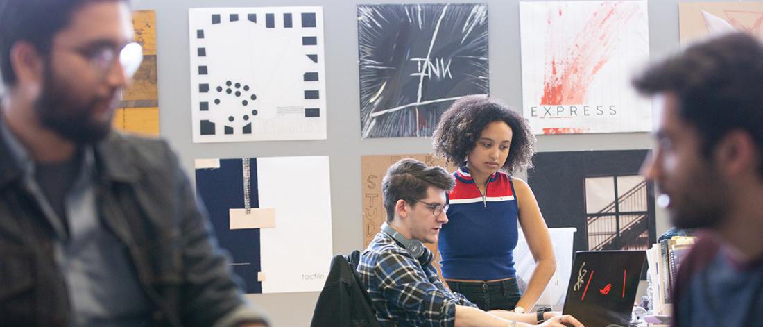 Professor speaking with student in classroom.