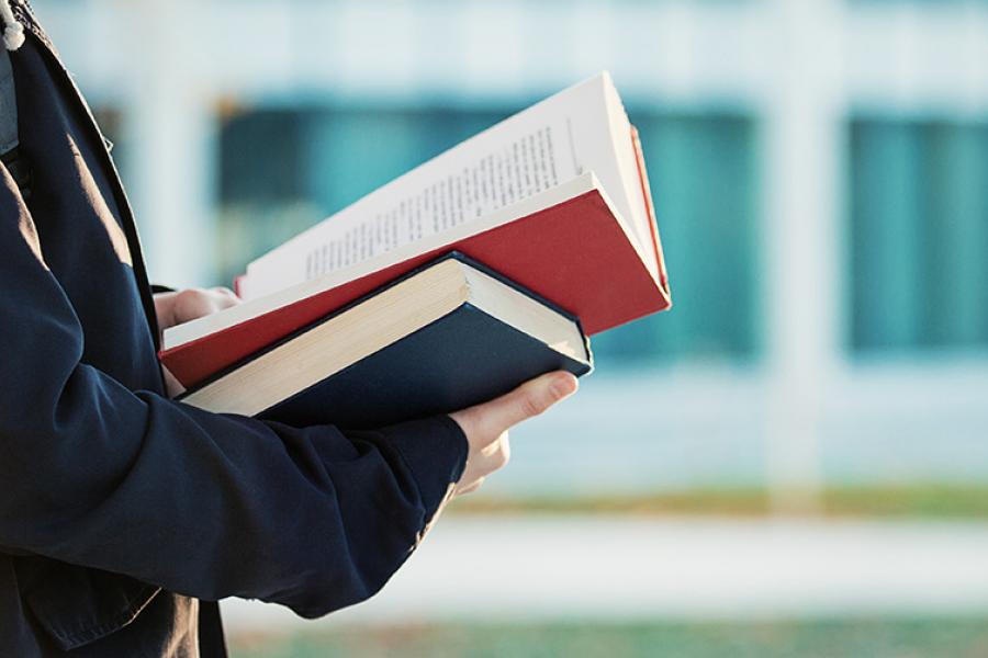 Student holding textbook outside.