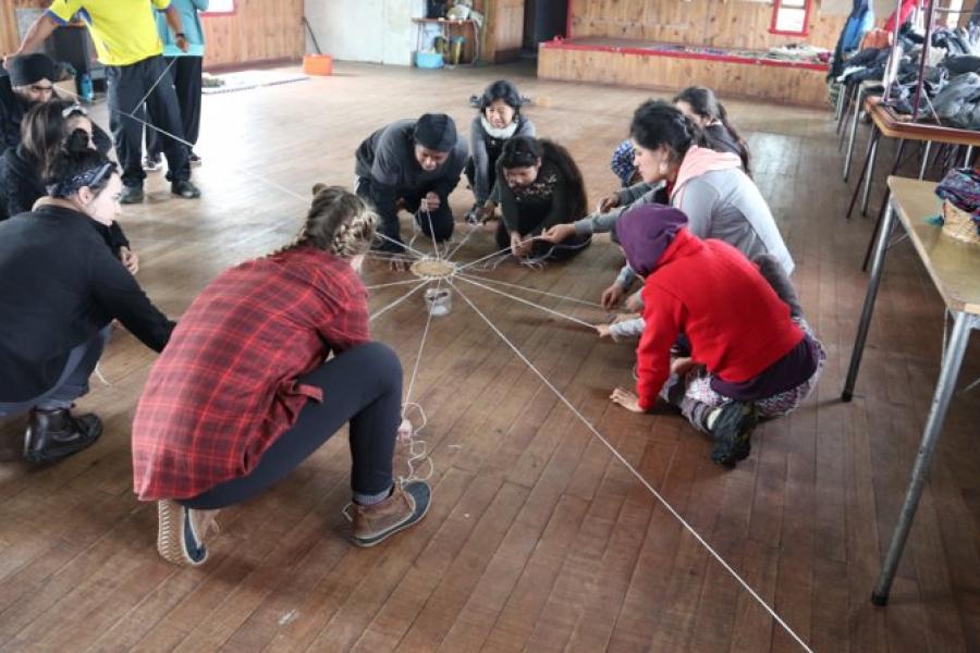 Instructor and students doing a string activity on a hardwood floor.