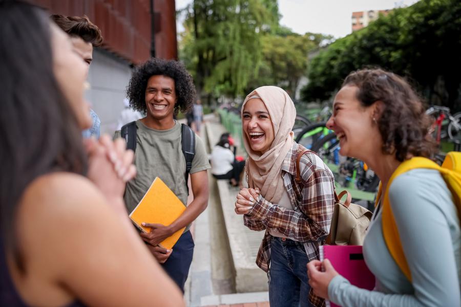 Diverse group of students laughing outside of a building.