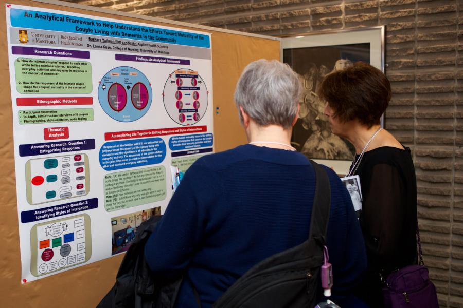 A graduate student discusses her research poster with a Symposium attendee.