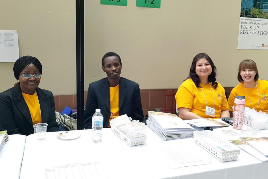 Four students volunteer at the registration desk during the spring research symposium.