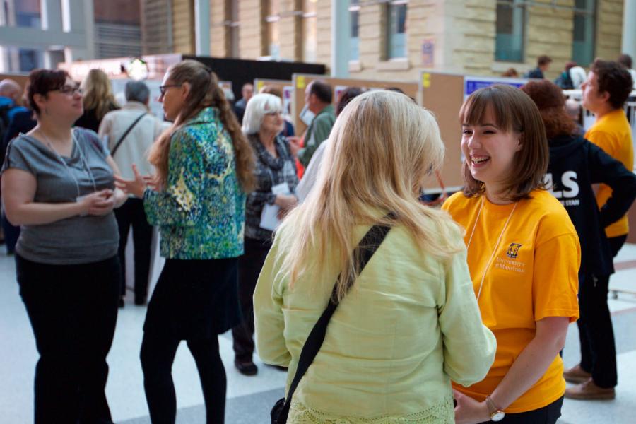 A student volunteer assists a symposium attendee during the spring research symposium.