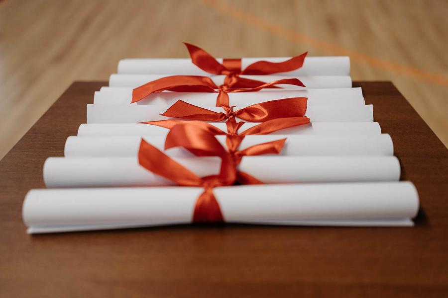 Seven scrolls wrapped with a red ribbon placed on top of a table.