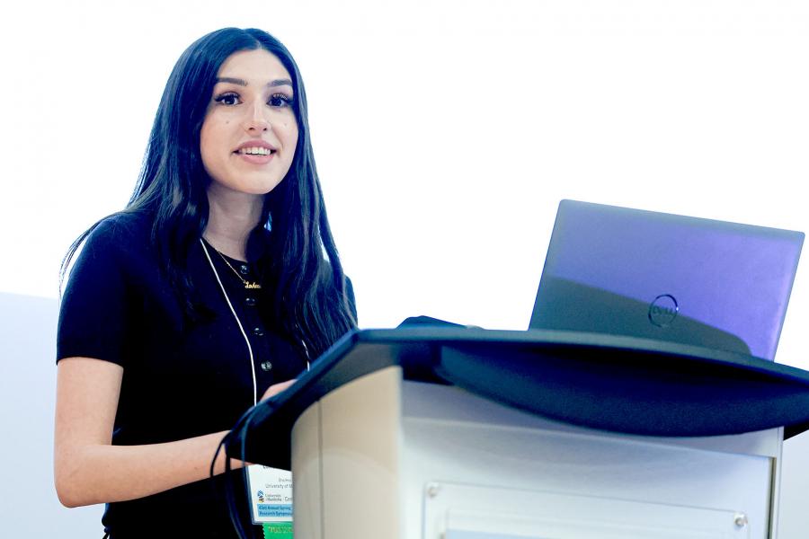 Student volunteer is standing at the podium for the Symposium. A part of the photo was edited with AI.