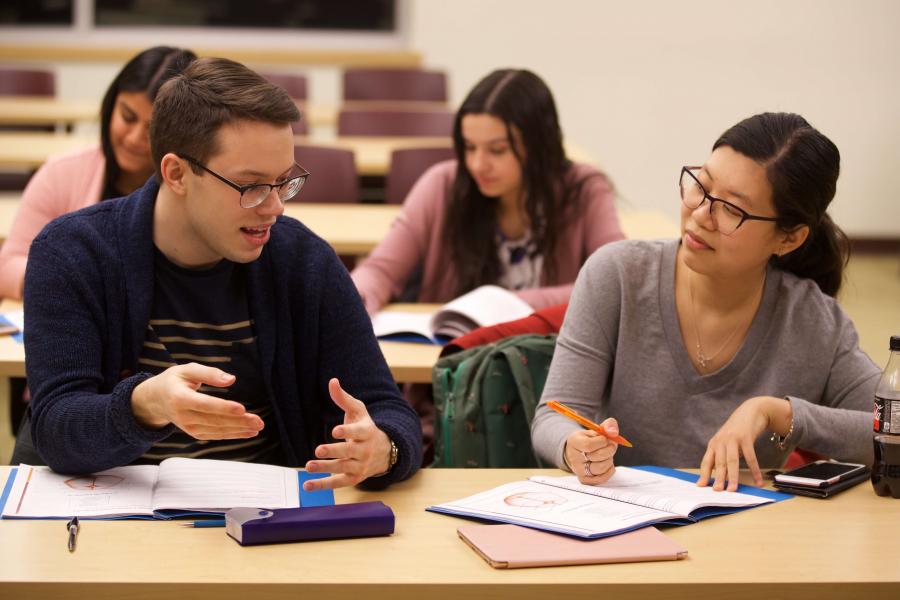 Two students in a classroom having a discussion.