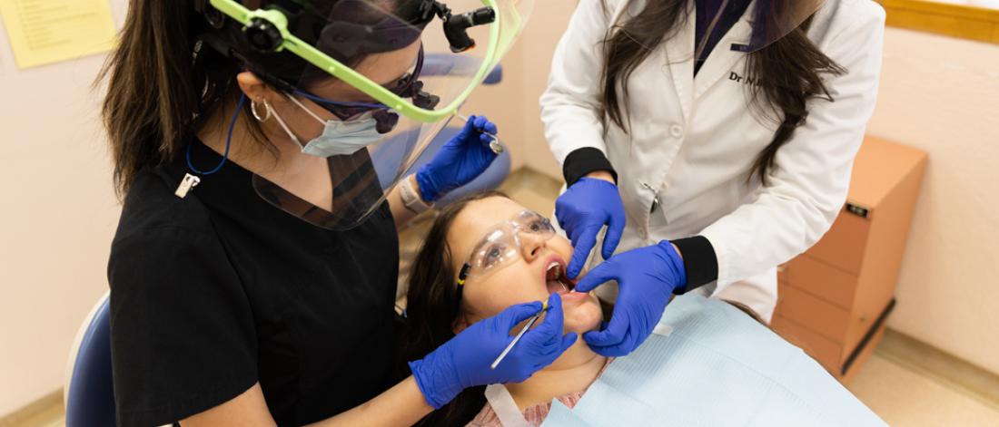 A dentist and a dental student working on a dental patient.