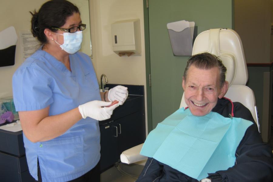 A dental hygienist treating a smiling senior dental patient.
