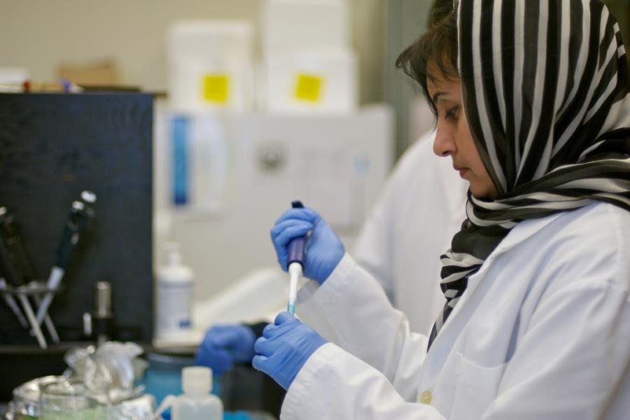 Researcher in a lab using a pipette.