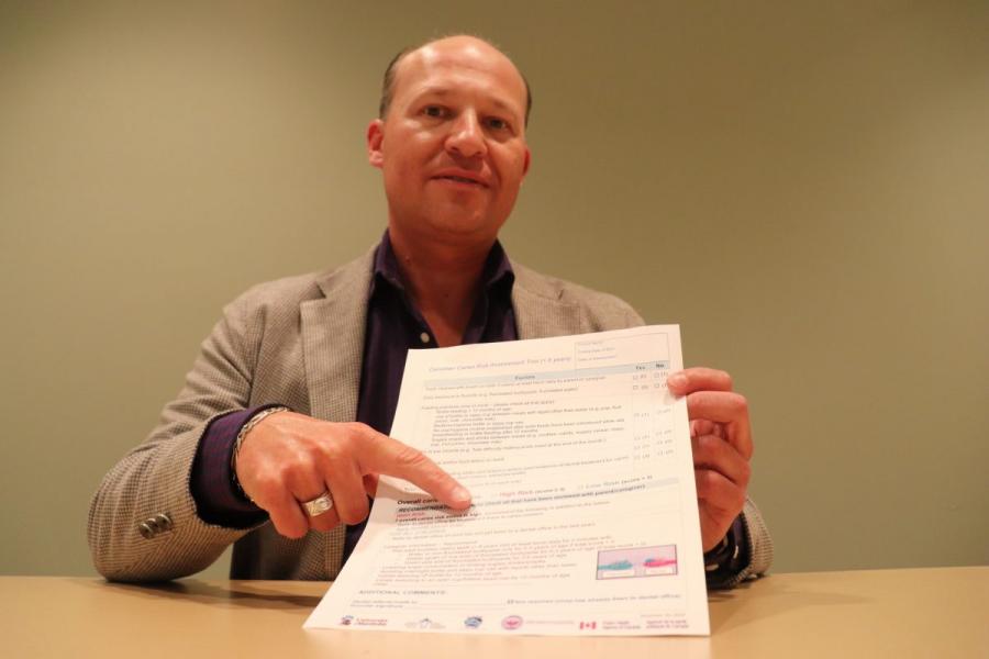 A man seated at a table, pointing to a document.