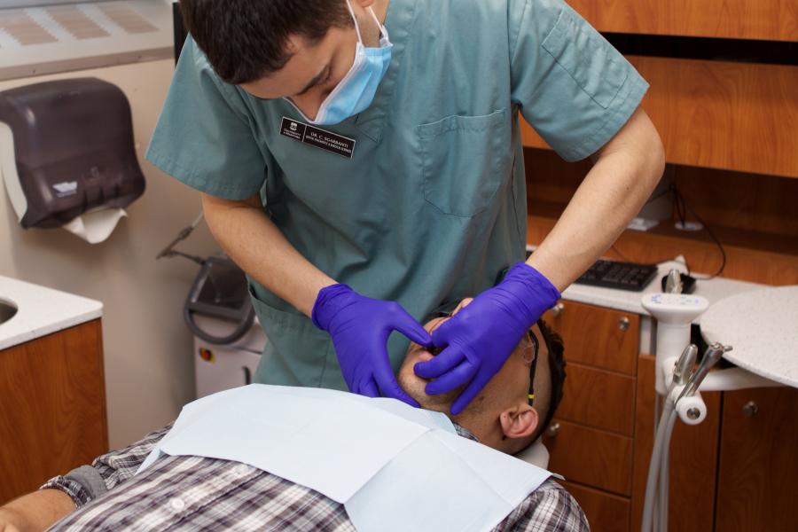 A dentist doing an oral exam on a patient laying in a dental chair.