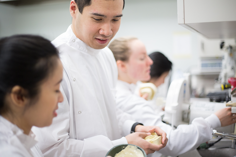 Two students in lab coats working on dental casting.