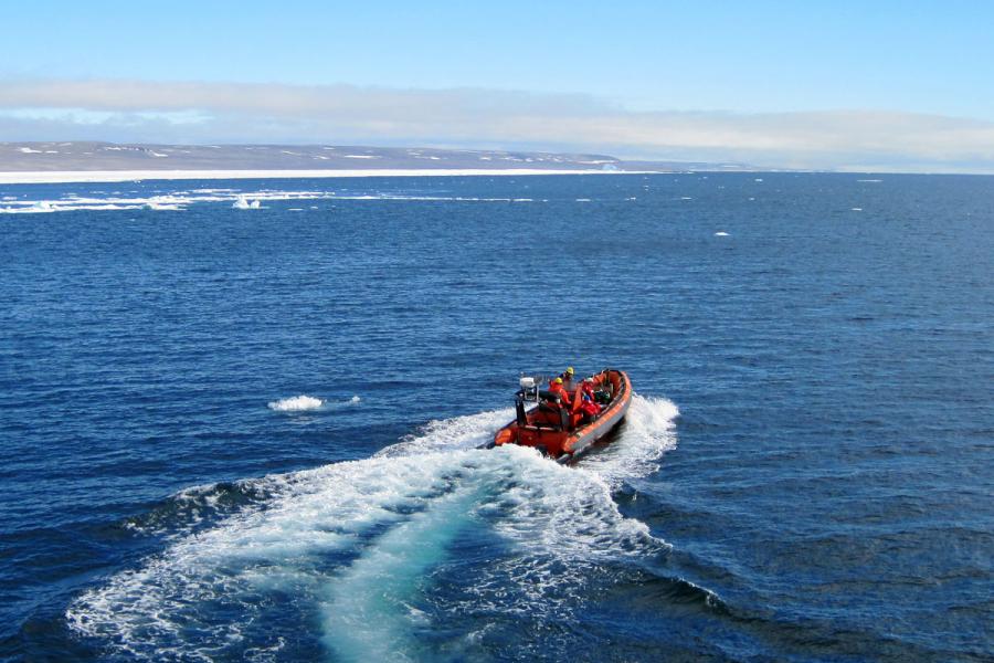 researchers driving away on a small boat.