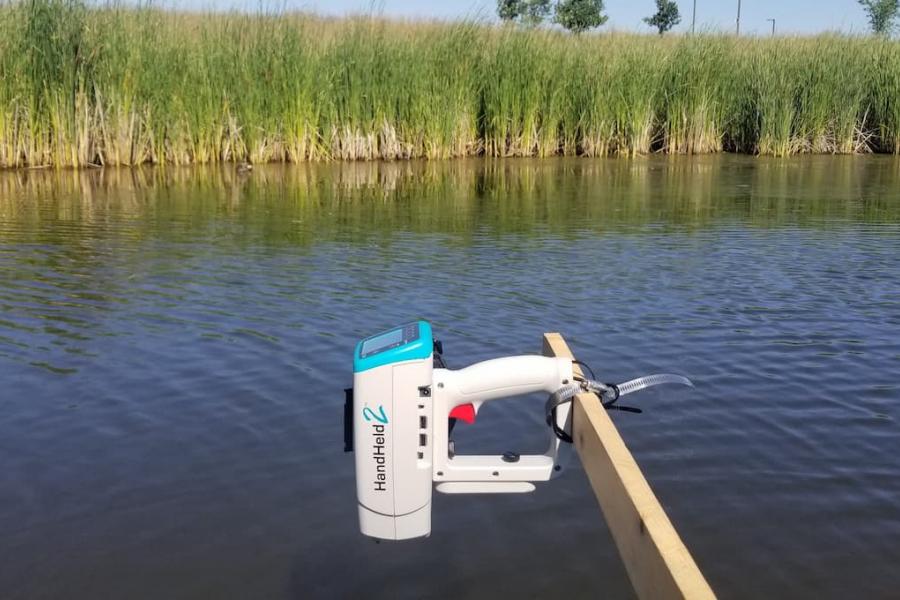 View of the ASD handheld spectroradiometer extended from the boat over the pond