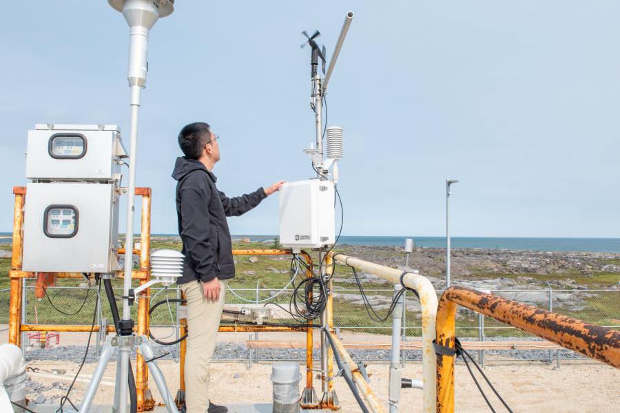 A person looking out to the surrounding landscape in Churchill while holding a piece of equipment.