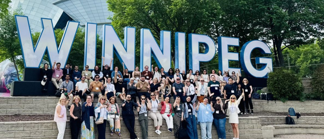 people in front of giant winnipeg sign