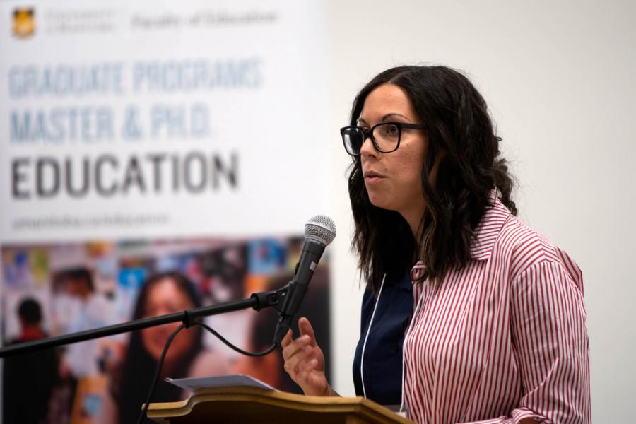 A PhD students stands at a podium talking. 