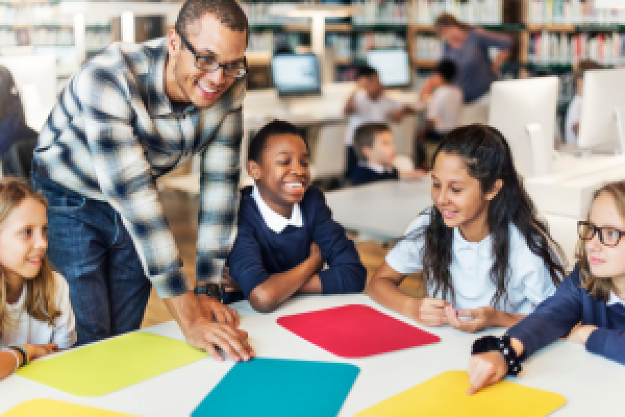 teacher with students smiling at a table
