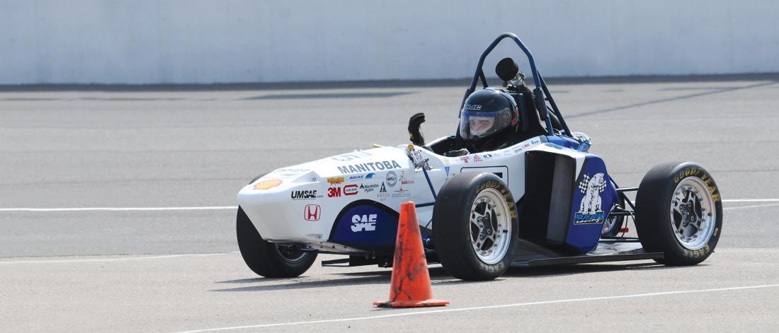 A formula one style race car outside on a test track. 